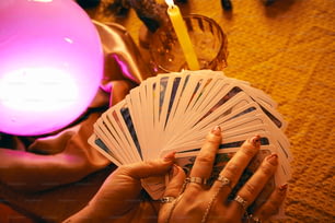 a woman holding a deck of cards next to a candle