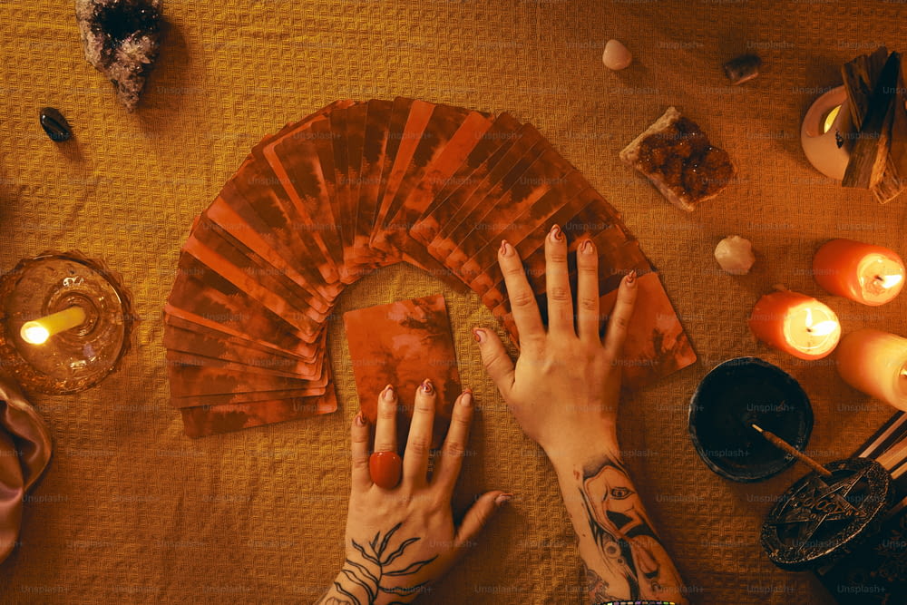 a person's hands on a table with a fan and candles