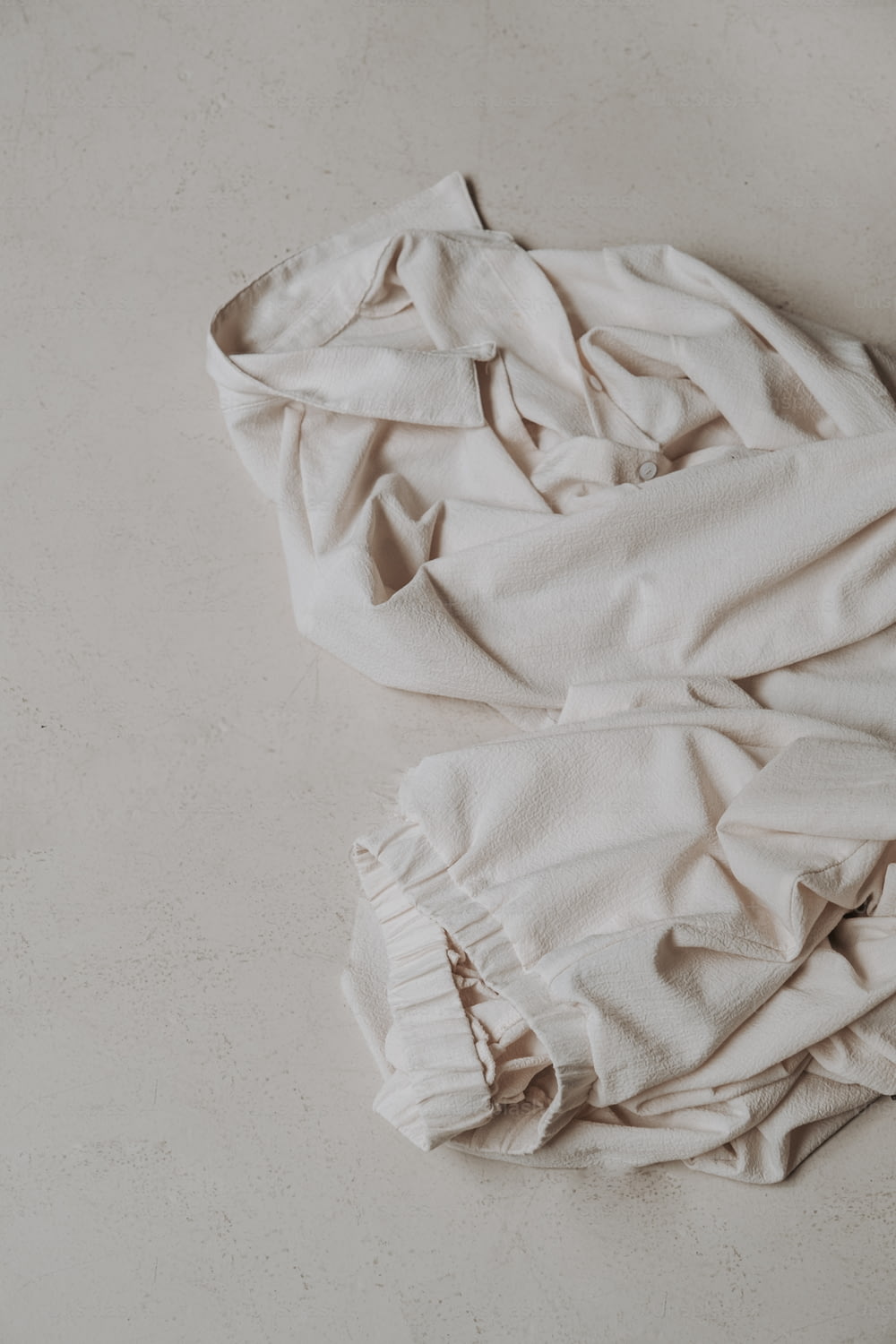 a white shirt laying on top of a white floor