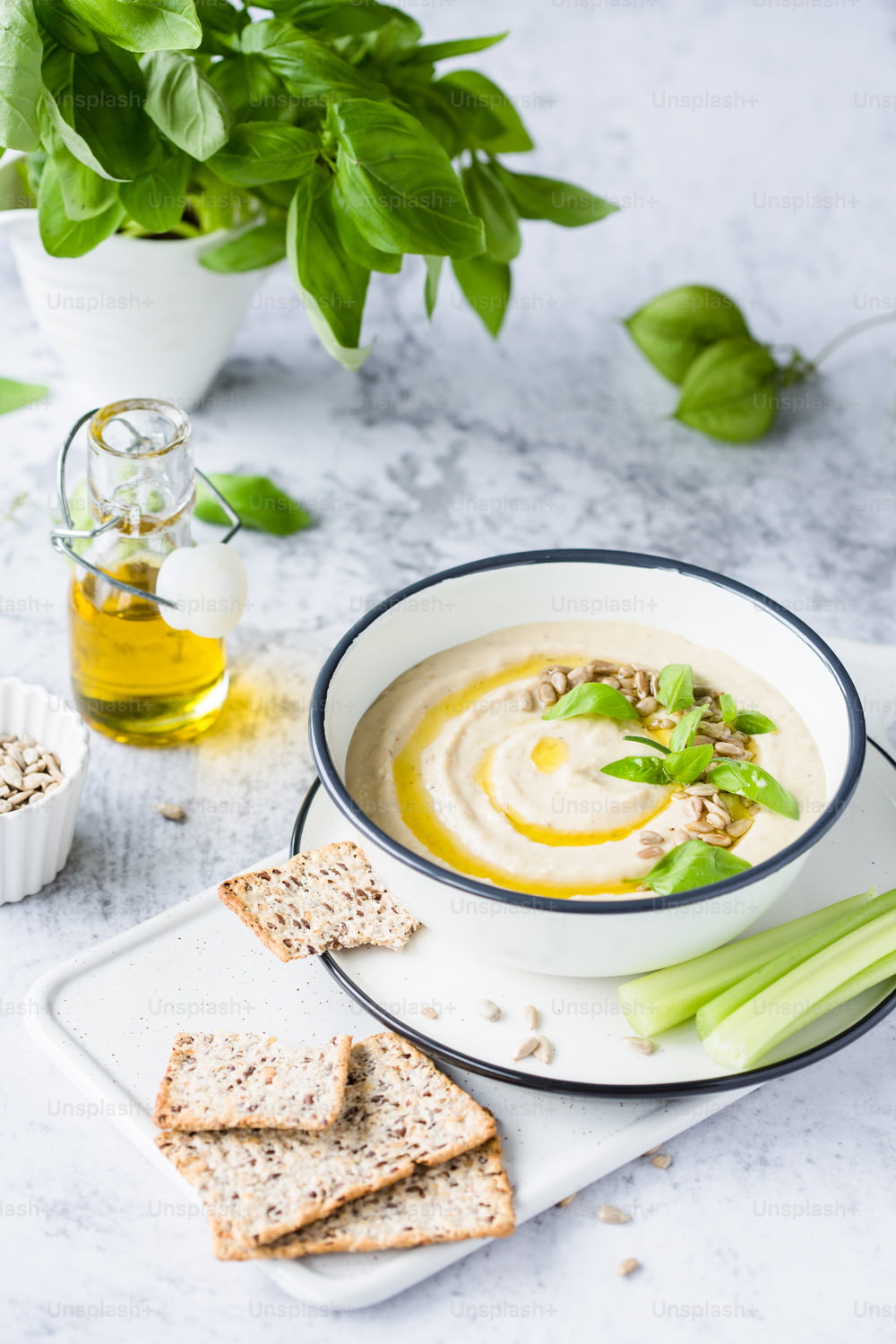 a bowl of hummus soup with celery and crackers