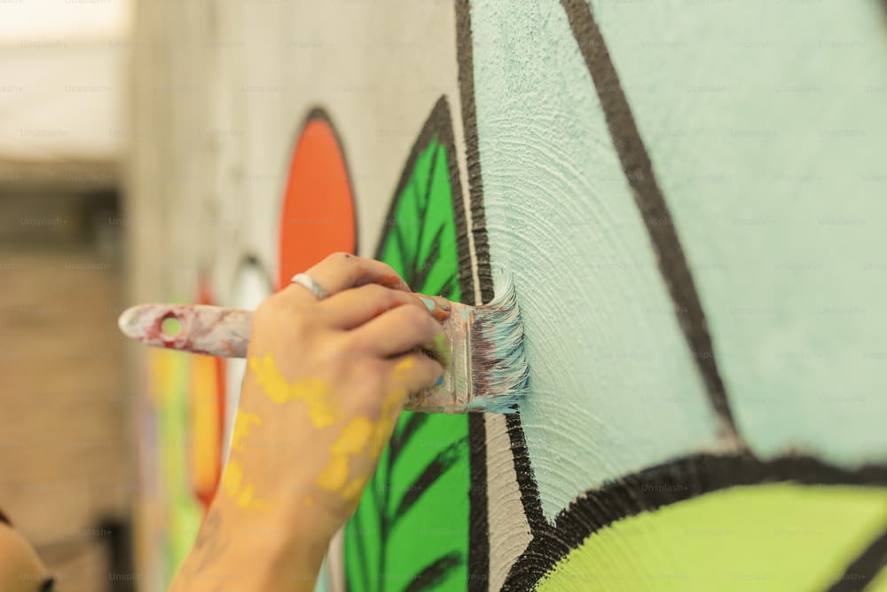 a woman painting a wall with a brush