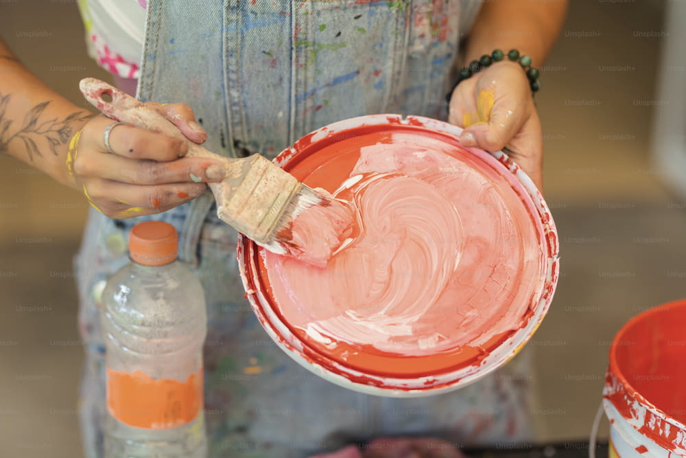 Une femme peint un bol rouge avec un pinceau