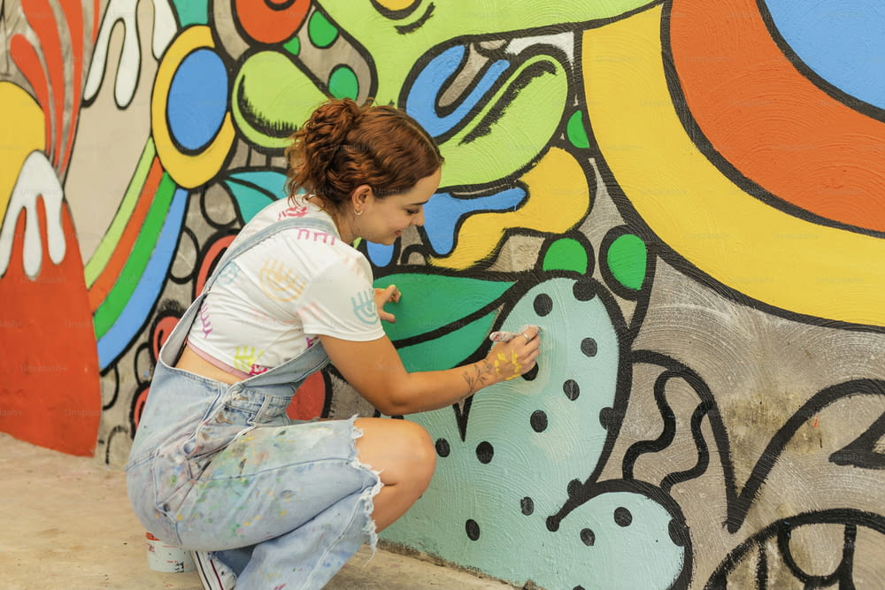 a woman kneeling down in front of a colorful wall