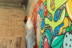a woman painting a mural on a brick wall