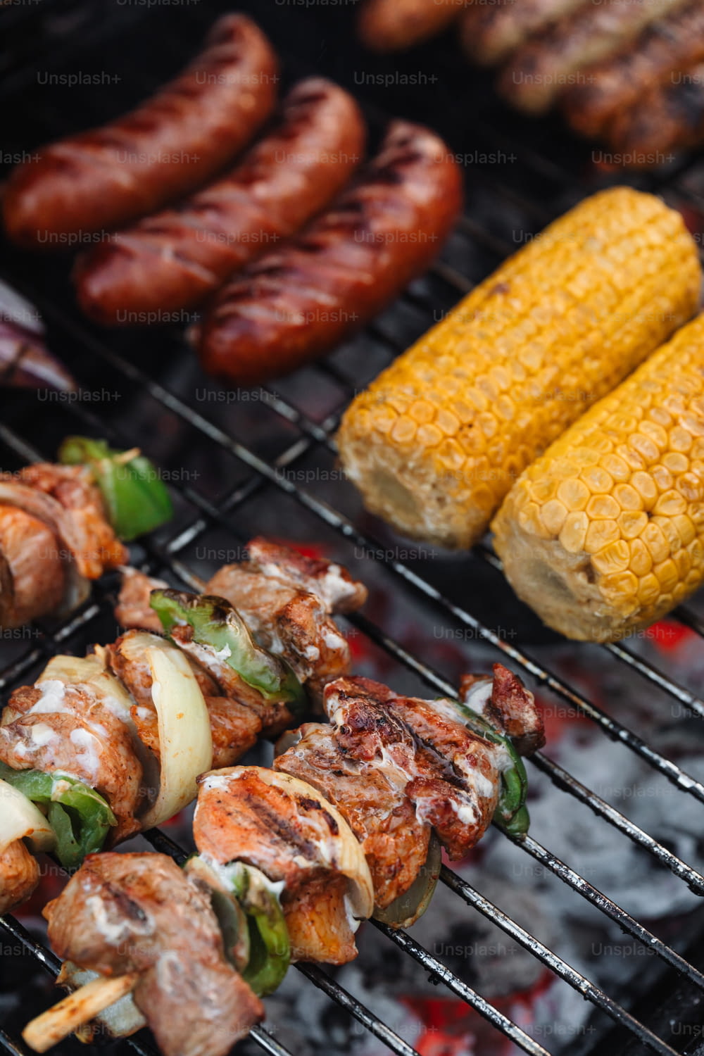 a bbq grill with corn, corn on the cob, and hot dogs