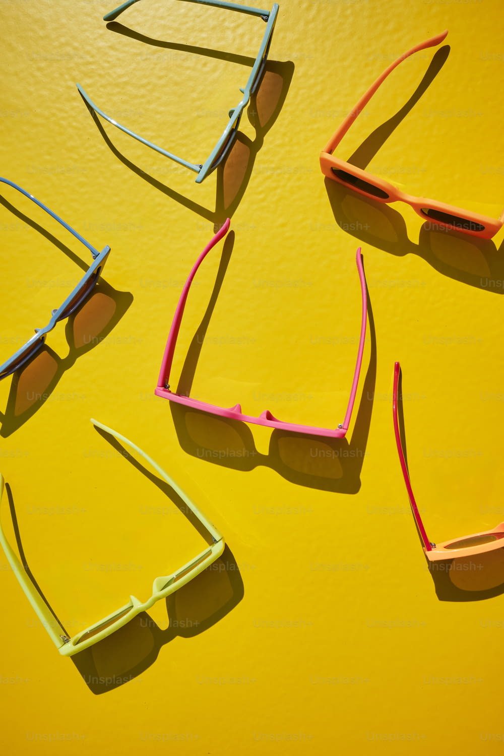 Quattro paia di occhiali da sole seduti sopra una superficie gialla