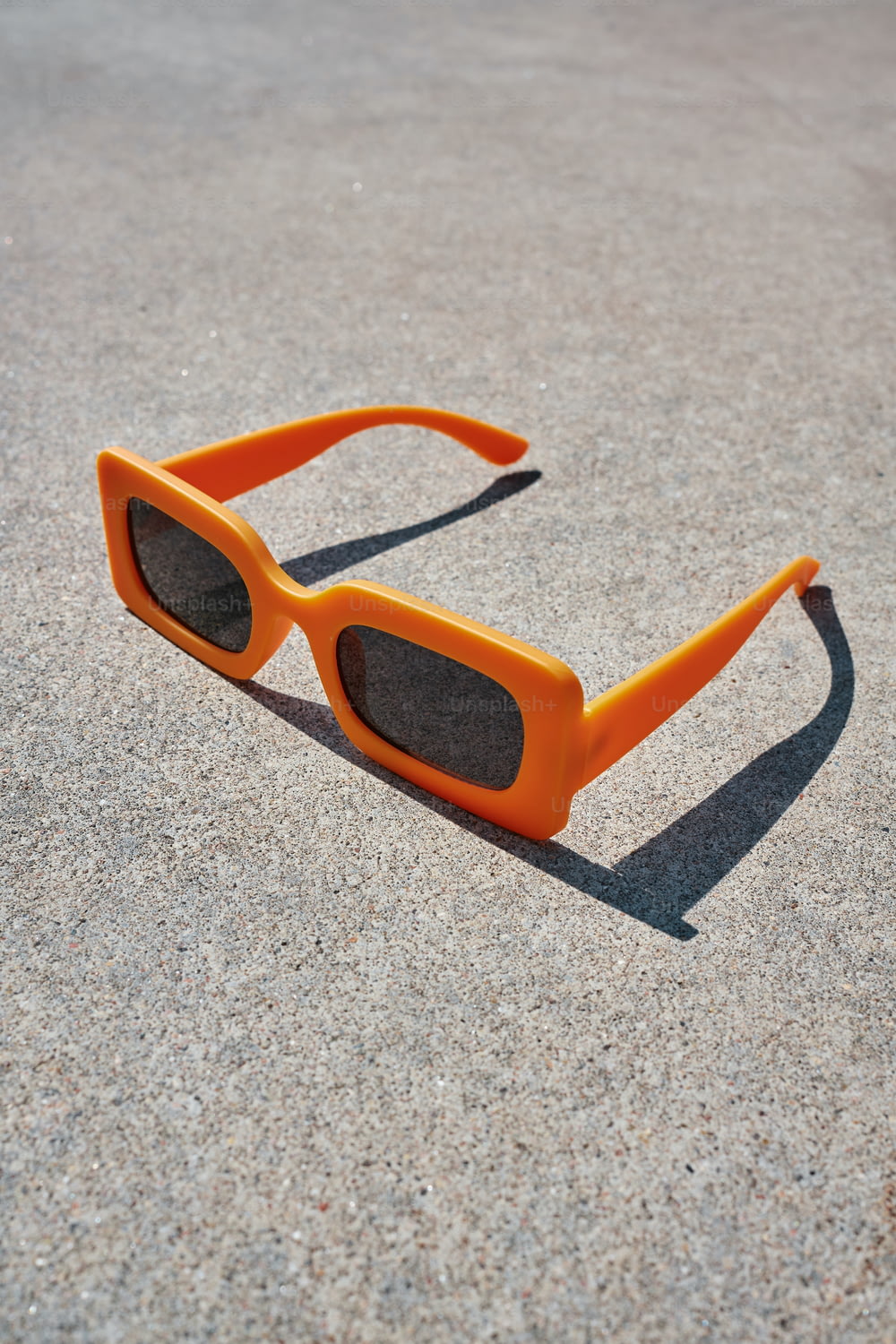 a pair of orange sunglasses laying on the ground
