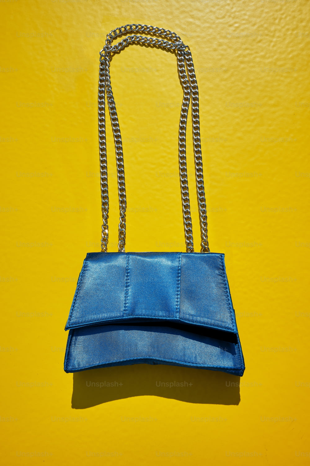 a blue purse hanging on a yellow wall