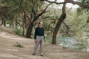 a man standing on a dirt road next to a river