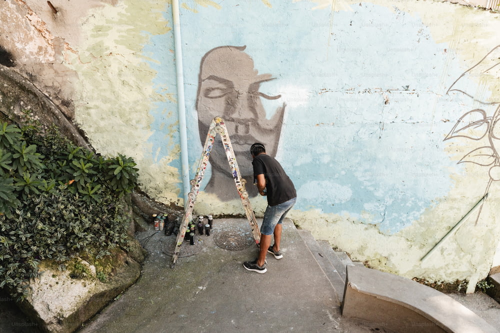 Ein Mann, der ein Wandgemälde an der Seite eines Gebäudes malt