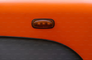 Un primer plano de un coche naranja con una luz encendida