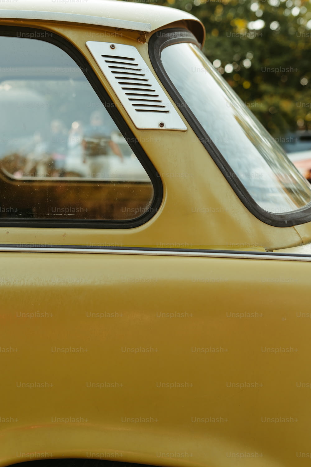 Nahaufnahme eines gelben Autos mit einem Hund, der seinen Kopf aus dem Fenster streckt