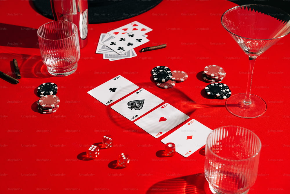 un tavolo rosso sormontato da carte e bicchieri da vino