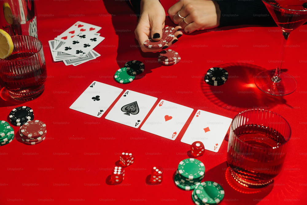 Un tavolo rosso sormontato da carte e bicchieri di vino
