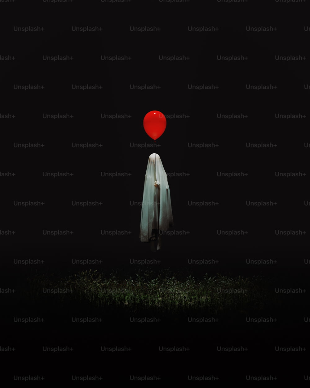 uma pessoa em pé no escuro com um balão vermelho na cabeça