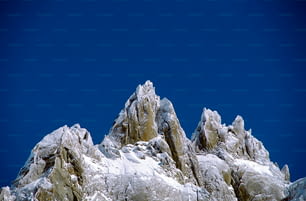 una montaña muy alta cubierta de nieve bajo un cielo azul