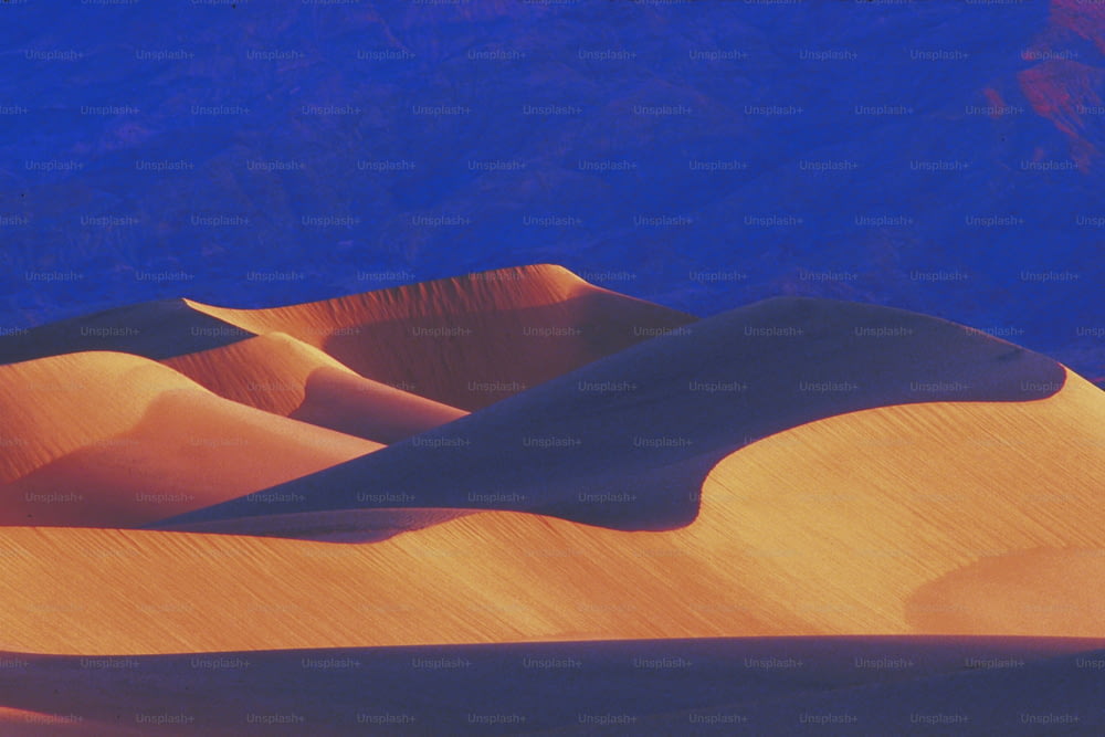 Una vista di una duna di sabbia con le montagne sullo sfondo