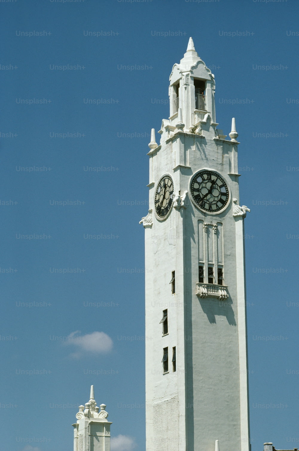Ein hoher weißer Glockenturm mit einer Uhr an jeder Seite