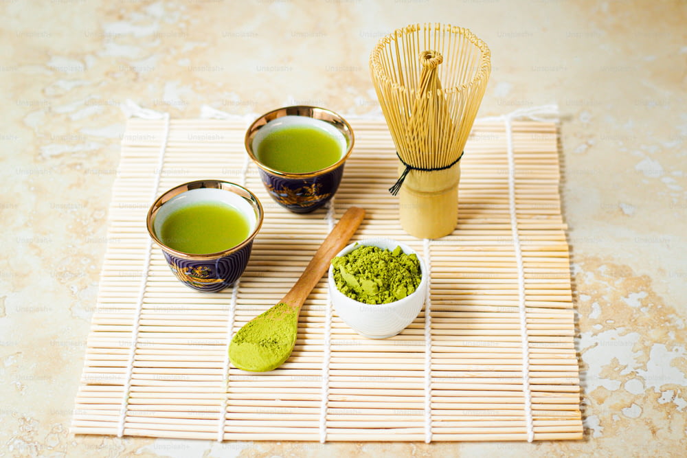 Tre tazze di tè verde su una stuoia di bambù