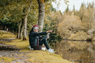 Un uomo seduto vicino a un lago che indica qualcosa