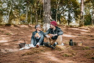 Due uomini seduti a terra nel bosco