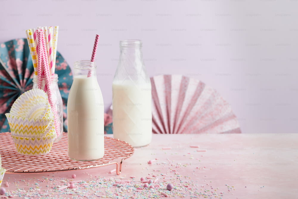 a pink table topped with a bottle of milk and a glass of milk