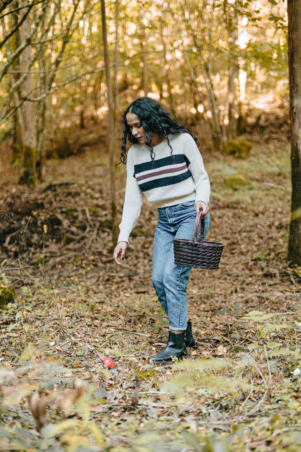 a woman walking through a forest carrying a basket