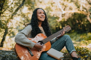 una donna seduta a terra che suona una chitarra