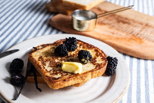 a white plate topped with french toast and blackberries