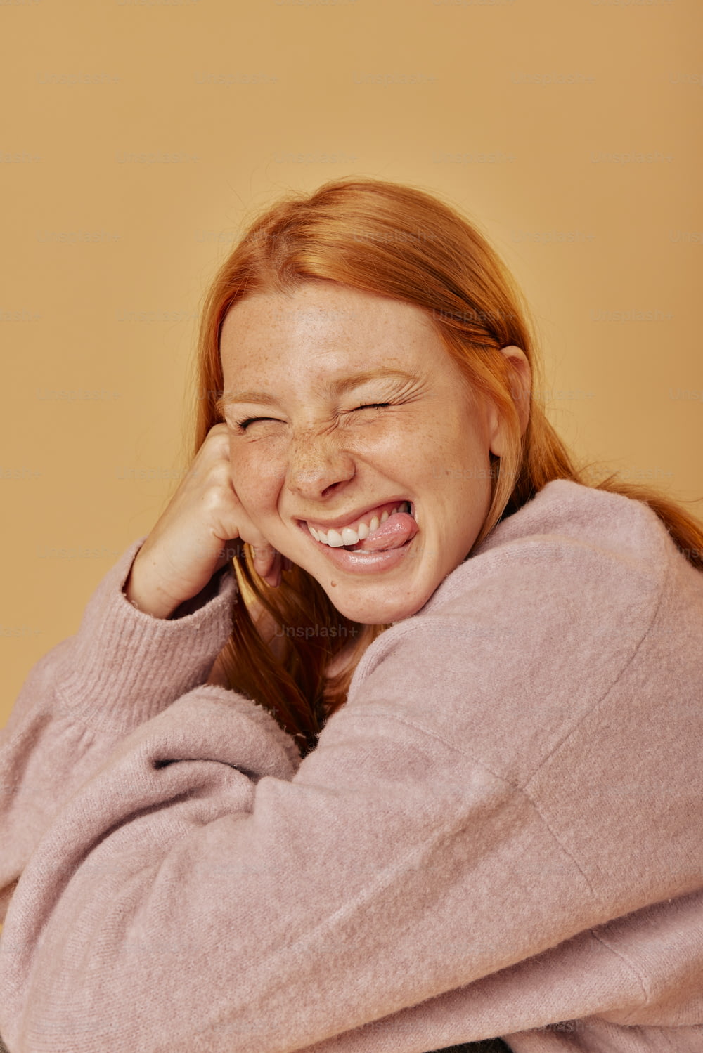 a woman is laughing and holding her head with her hands