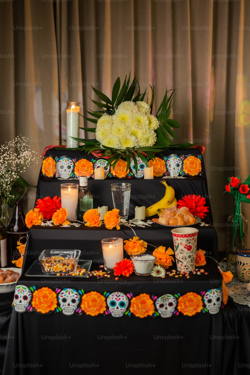 a table with candles, flowers, and skulls on it