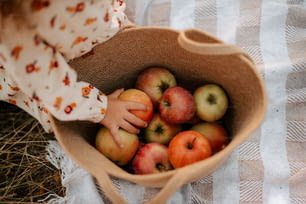une petite fille tenant un panier plein de pommes