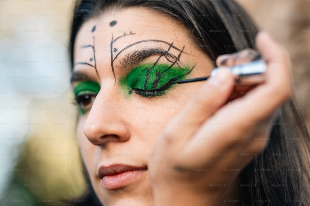 a woman with green makeup and a green eyeliner