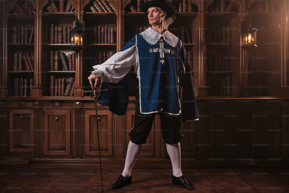 Ein Mann in einem Renaissance-Kostüm steht vor einem Bücherregal