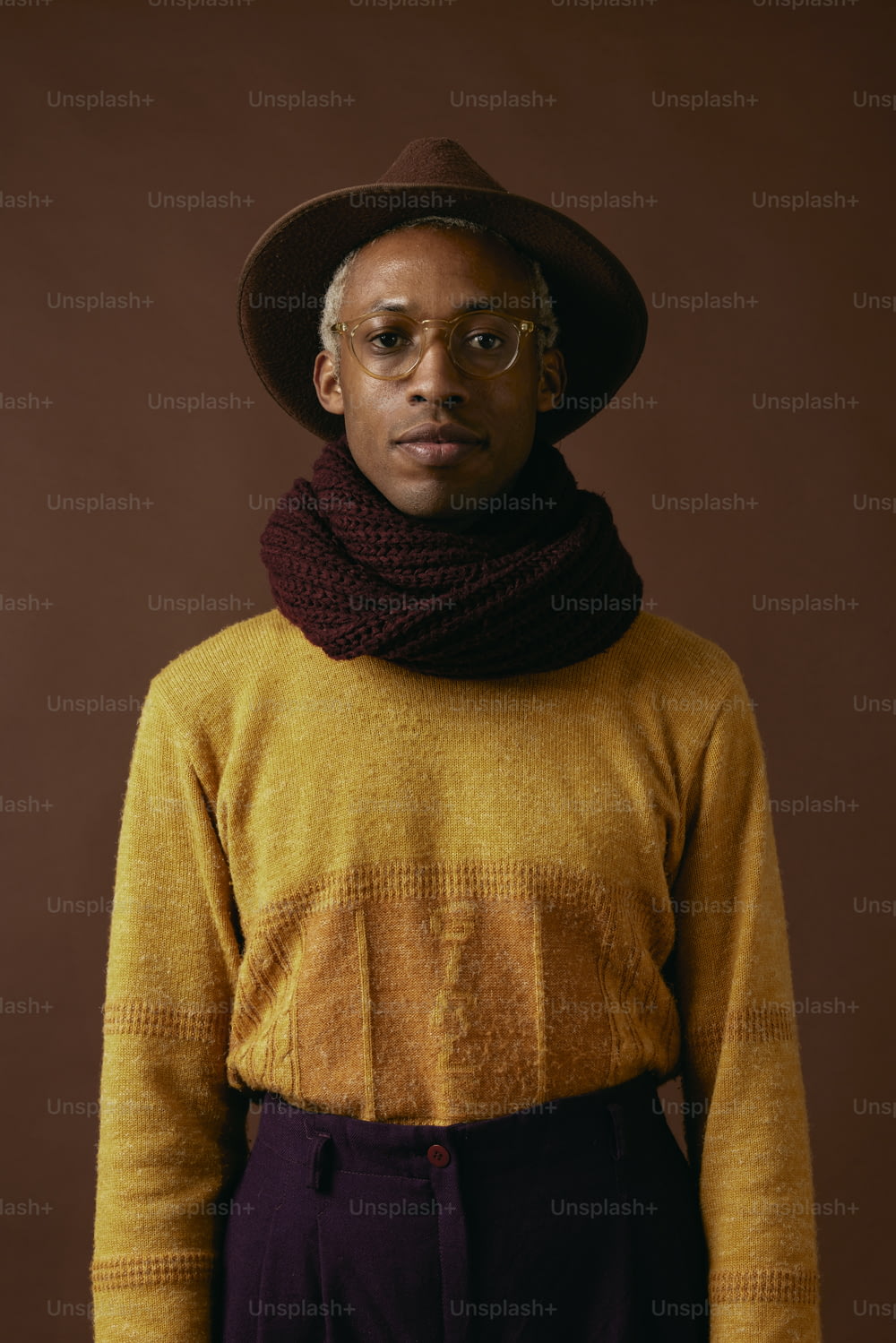 a man wearing a yellow sweater and a brown hat