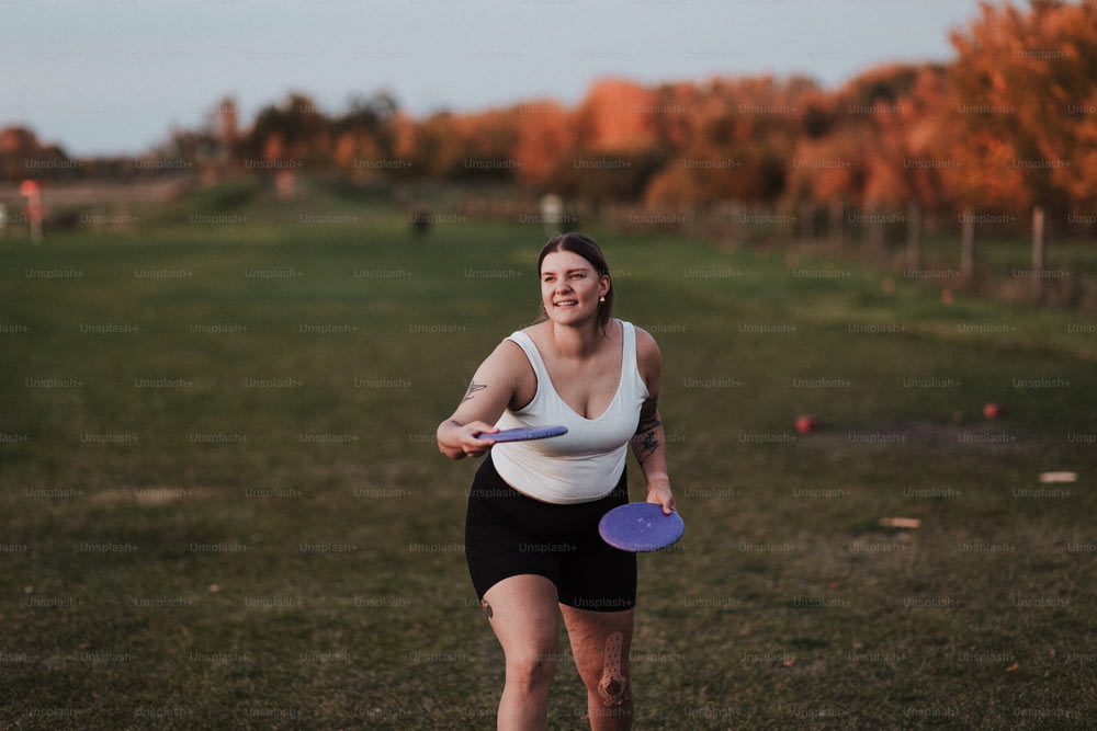 uma mulher segurando um frisbee roxo em cima de um campo