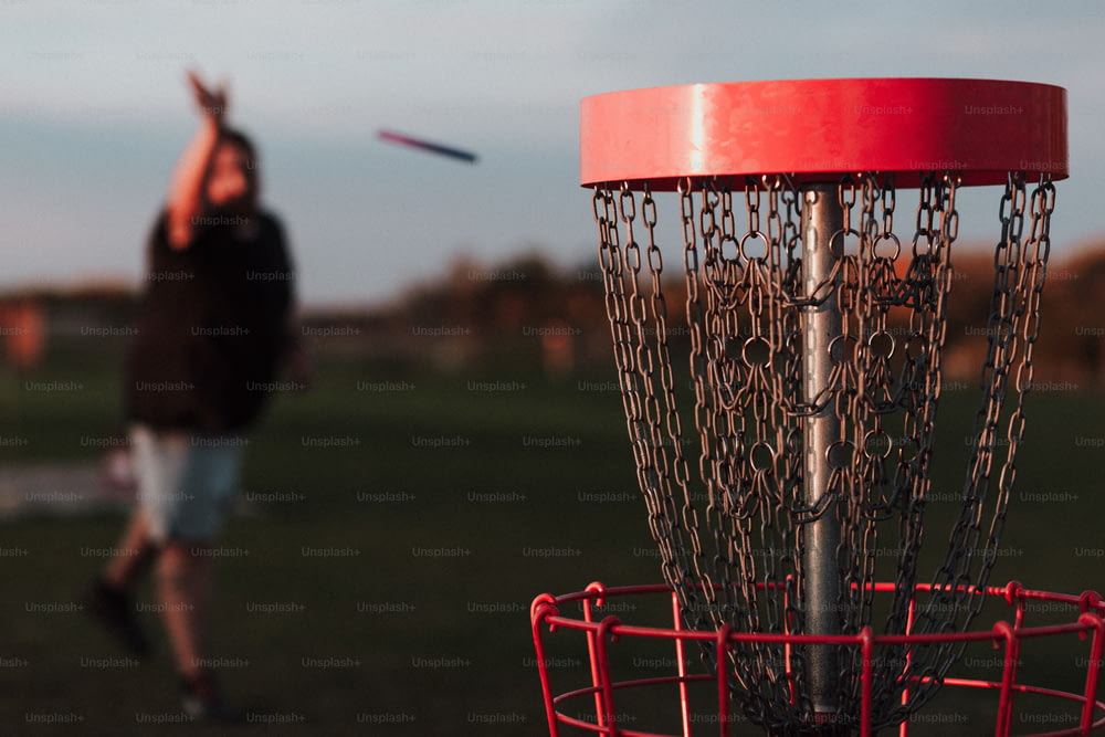 a man throwing a frisbee into a metal basket