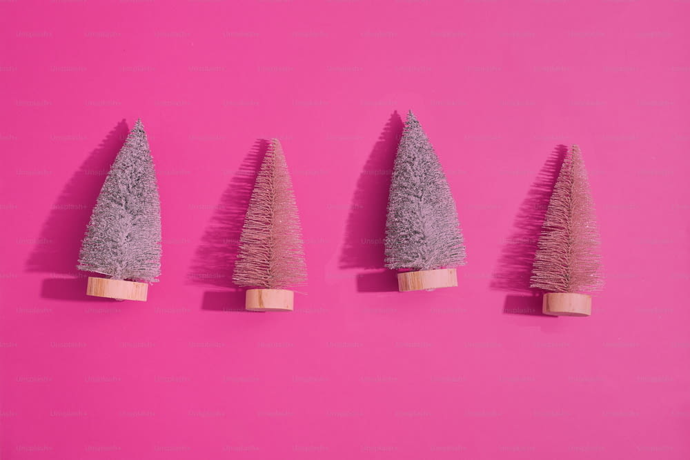 a group of three small trees sitting on top of a pink surface