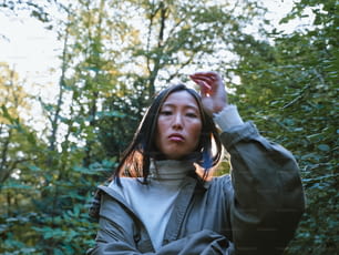 Une femme debout devant une forêt tenant un téléphone portable à l’oreille