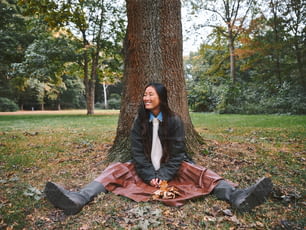 une femme assise par terre devant un arbre
