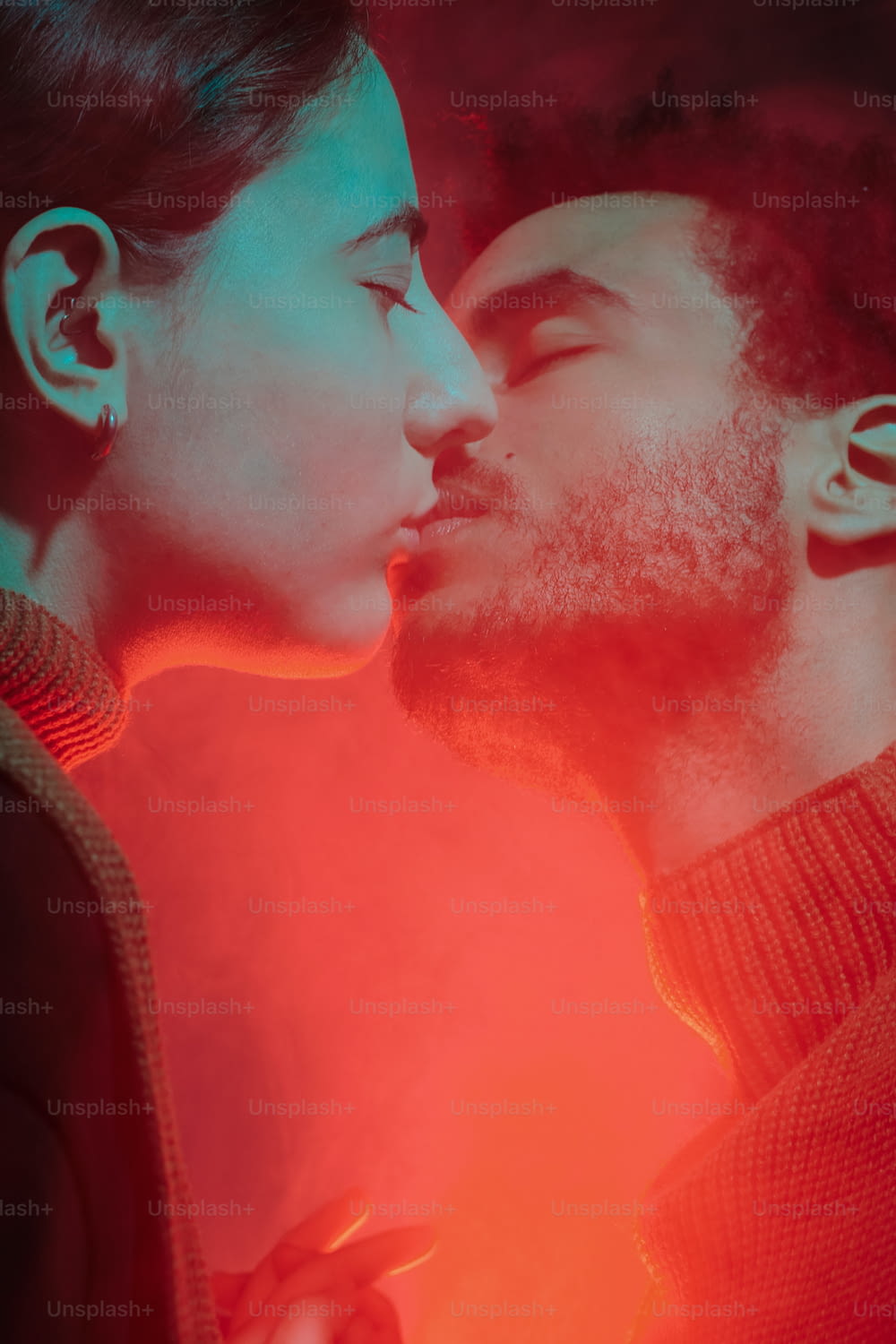 a man and a woman kissing in front of a red light