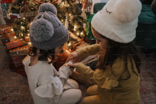 크리스마스 트리 앞에 앉아 있는 두 어린 소녀