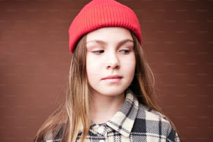 a young girl wearing a red hat and a plaid coat