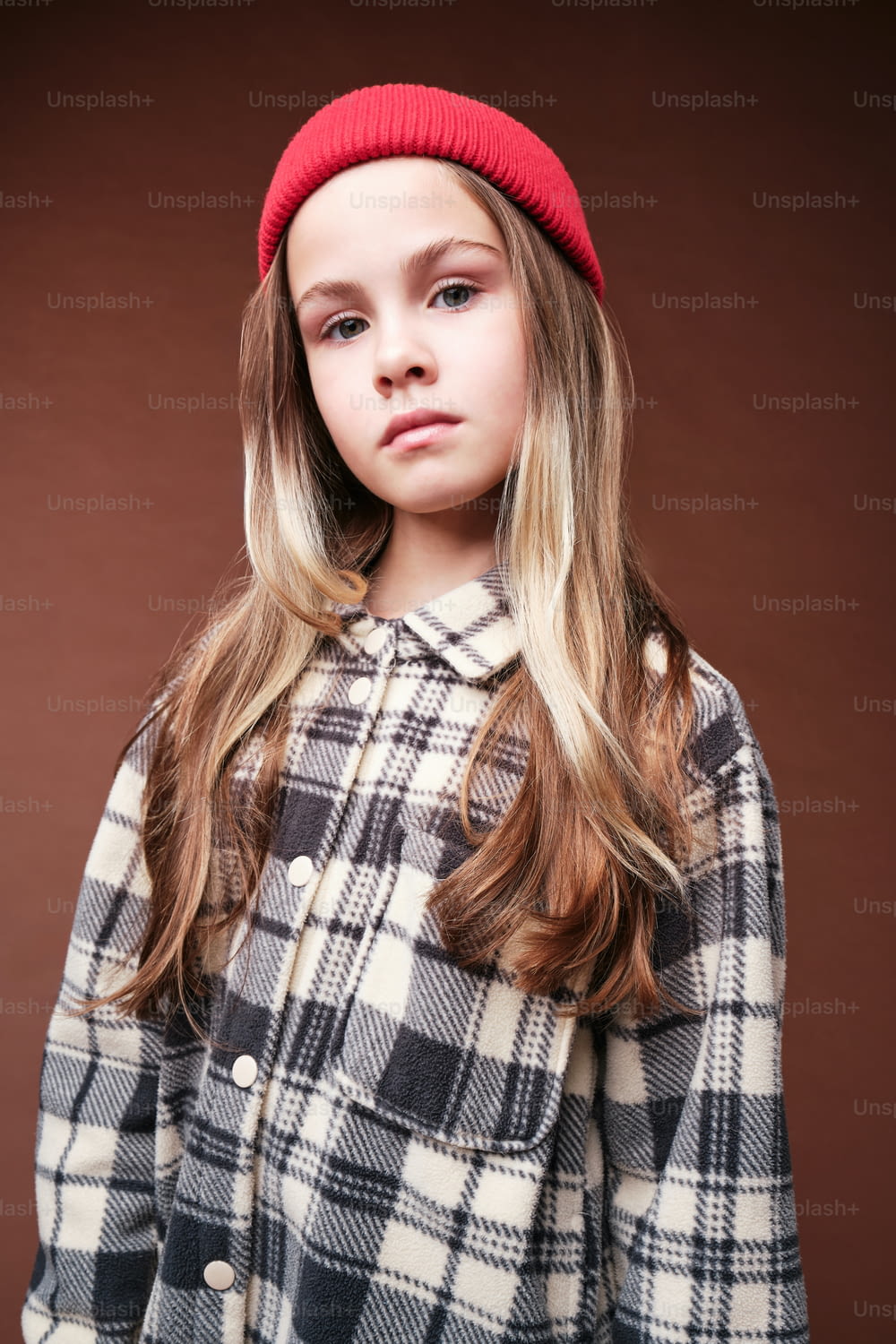 una giovane ragazza che indossa un cappotto a quadri e un berretto rosso
