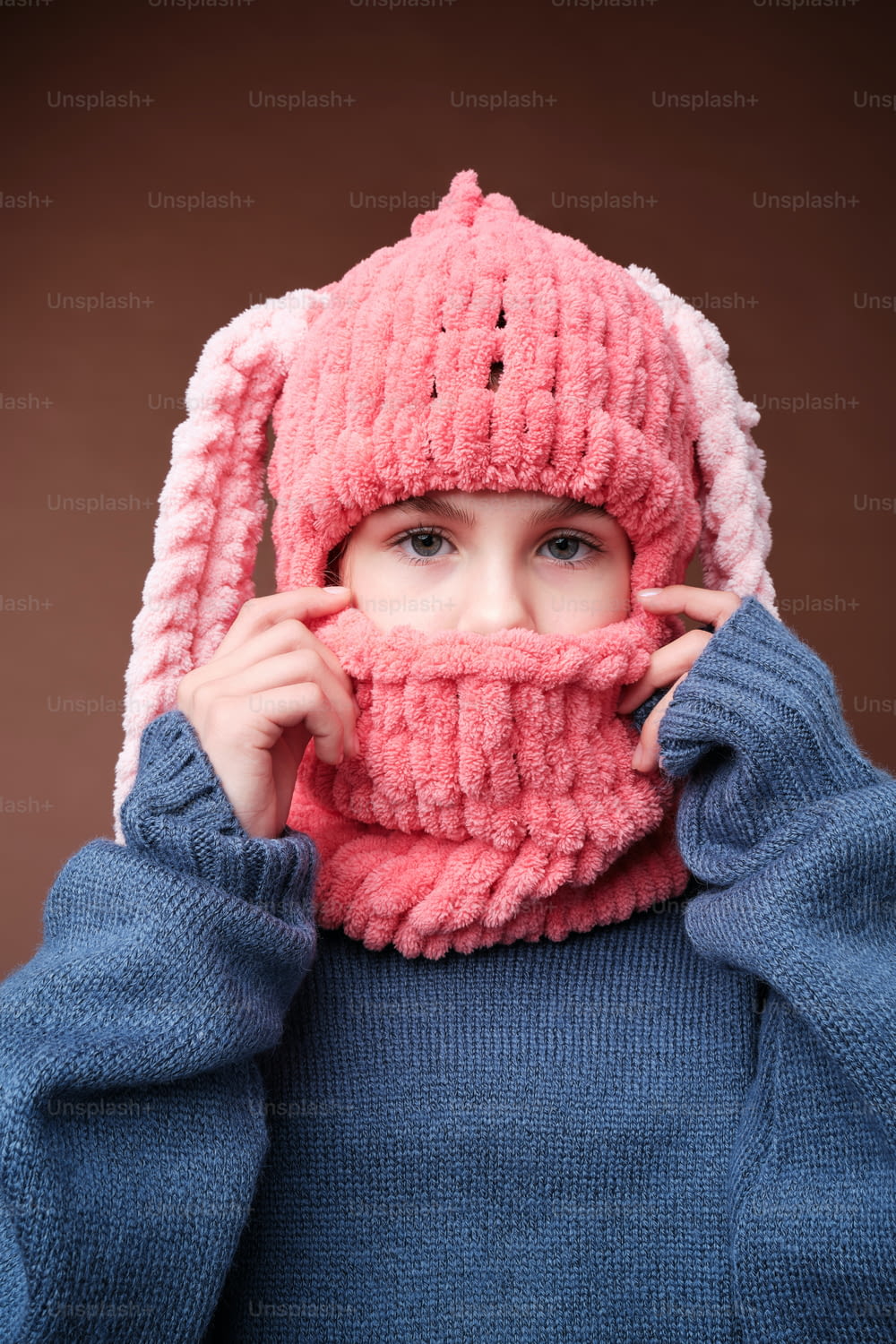 una giovane ragazza che indossa un cappello e una sciarpa lavorati a maglia rosa