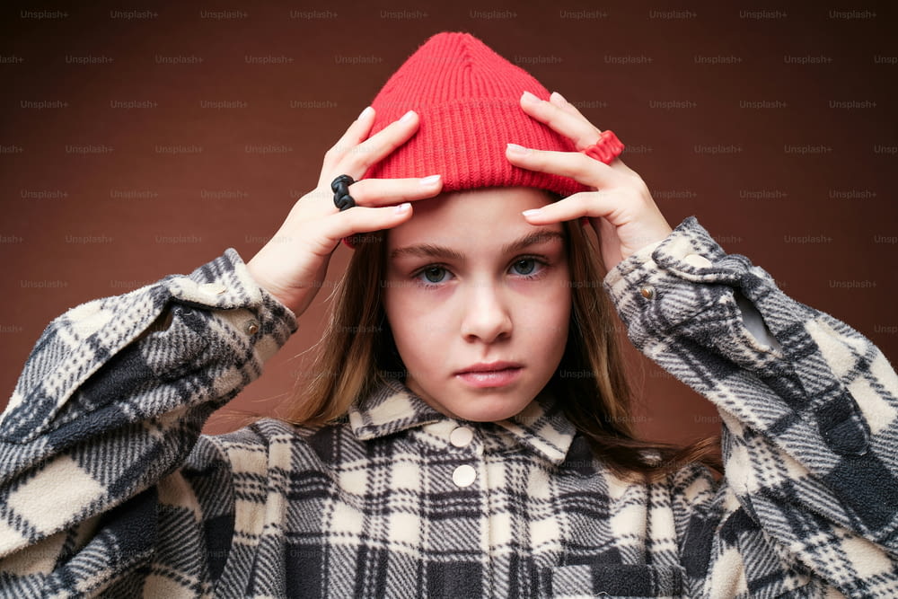 a young girl holding a red hat over her head