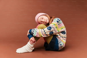 a young girl sitting on the ground with her head on a ball