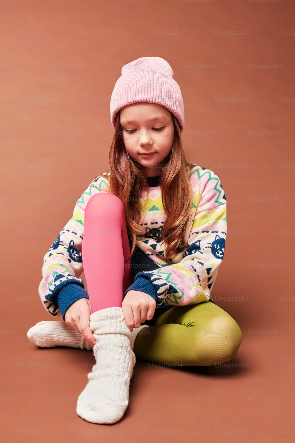 una bambina seduta a terra con un oggetto rosa