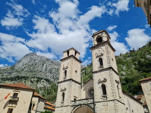 A low angle shot of Katedrala Svetog Tripuna cathedral on blue cloudy sky background in Kotor, Montenegro