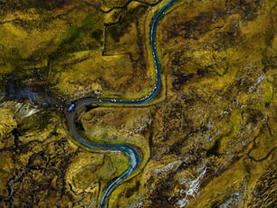 An aerial shot of a winding river flowing through a lush green landscape with an array of rocks, trees and other vegetation